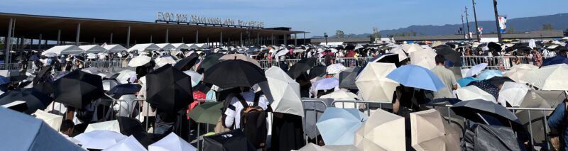 西ゲート前の朝の混雑。日差しが強いので日傘が多い。
