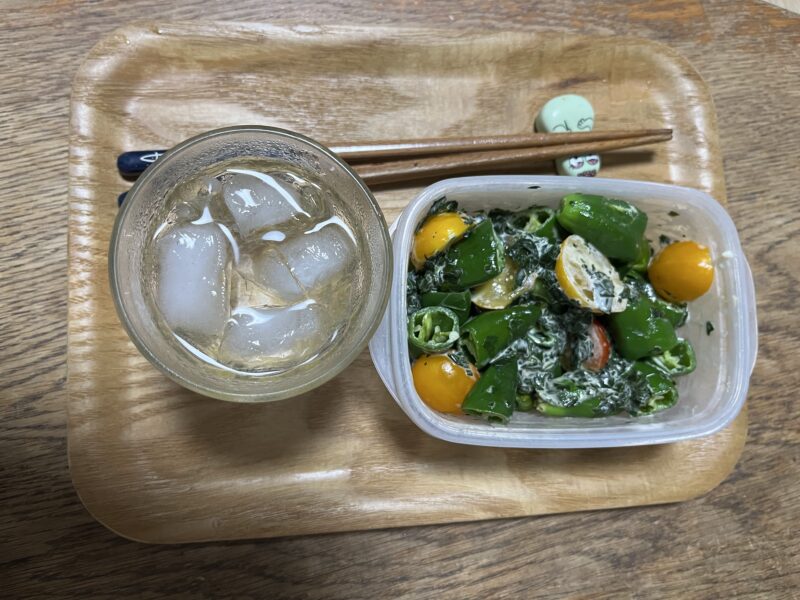 お酒とおつまみ。おつまみは自作のピーマンとトマトのマヨネーズあえ。お酒は日本酒のロック。