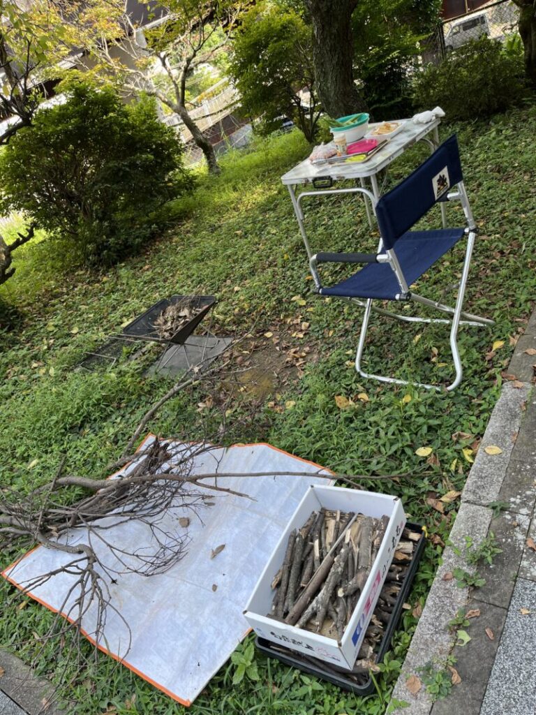 庭で焚き火準備。薪と焚き火台、テーブルに椅子をセット。食材も用意済み。